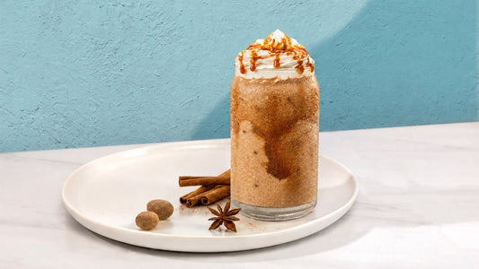 Pumpkin drink in a glass cup on a white plate with java chips and cinnamon.