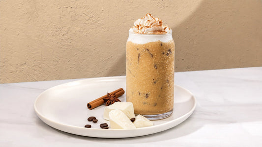 Pumpkin Drink on a white plate with White Chocolate, Coffee Beans, and Cinnamon.