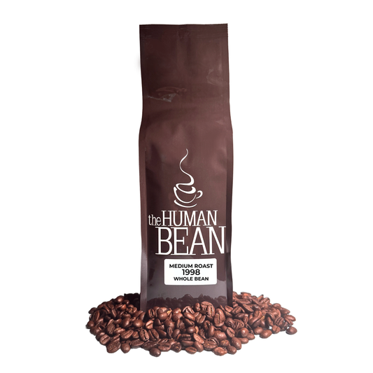 Coffee bag labeled 'the HUMAN BEAN Medium Roast 1998 Whole Bean' with coffee beans around on a white background
