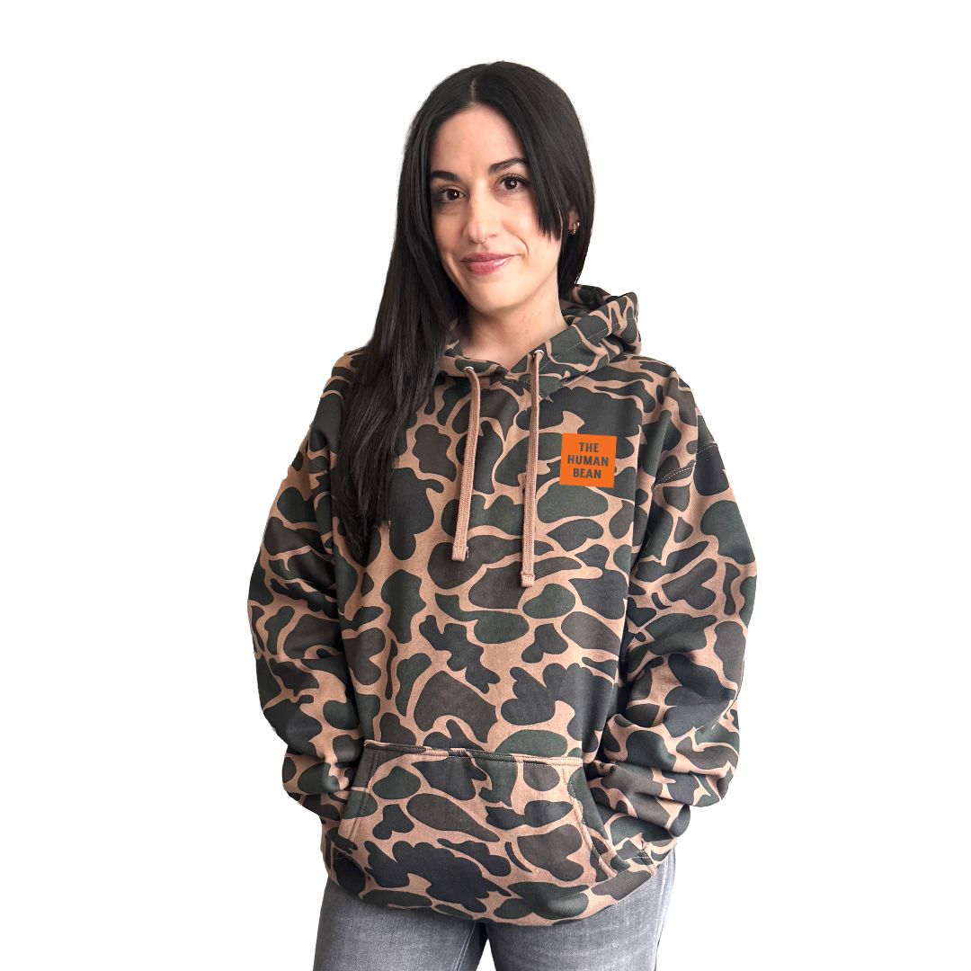Woman wearing a camouflage hoodie with a brand logo on a white background