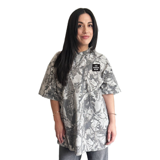 Woman wearing a camouflage-patterned shirt with a The Human Bean brand logo on a white background